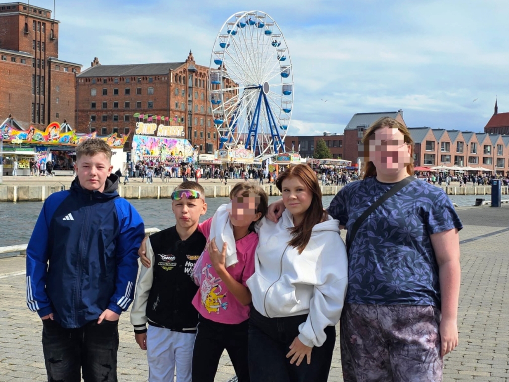 Gruppe von fünf Personen vor einem Kirmesgelände mit Riesenrad