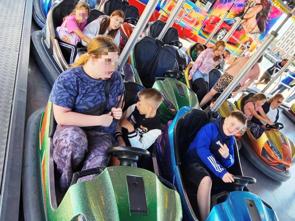 Kinder und Jugendliche in einem Vergnügungspark beim Autoscooter-Fahren.