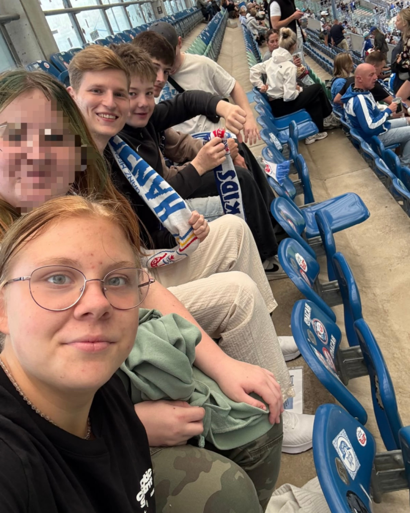 Jugendliche im Stadion auf einer Tribüne mit Schals.