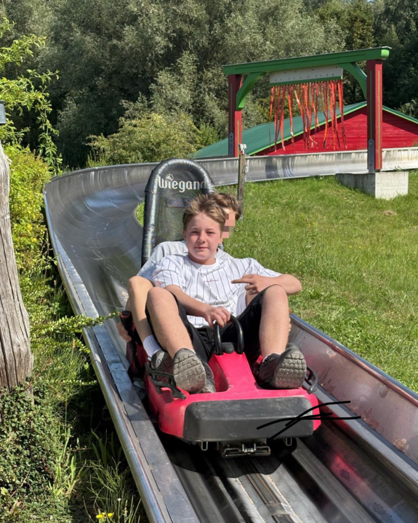 Zwei Personen fahren auf einer Sommerrodelbahn.