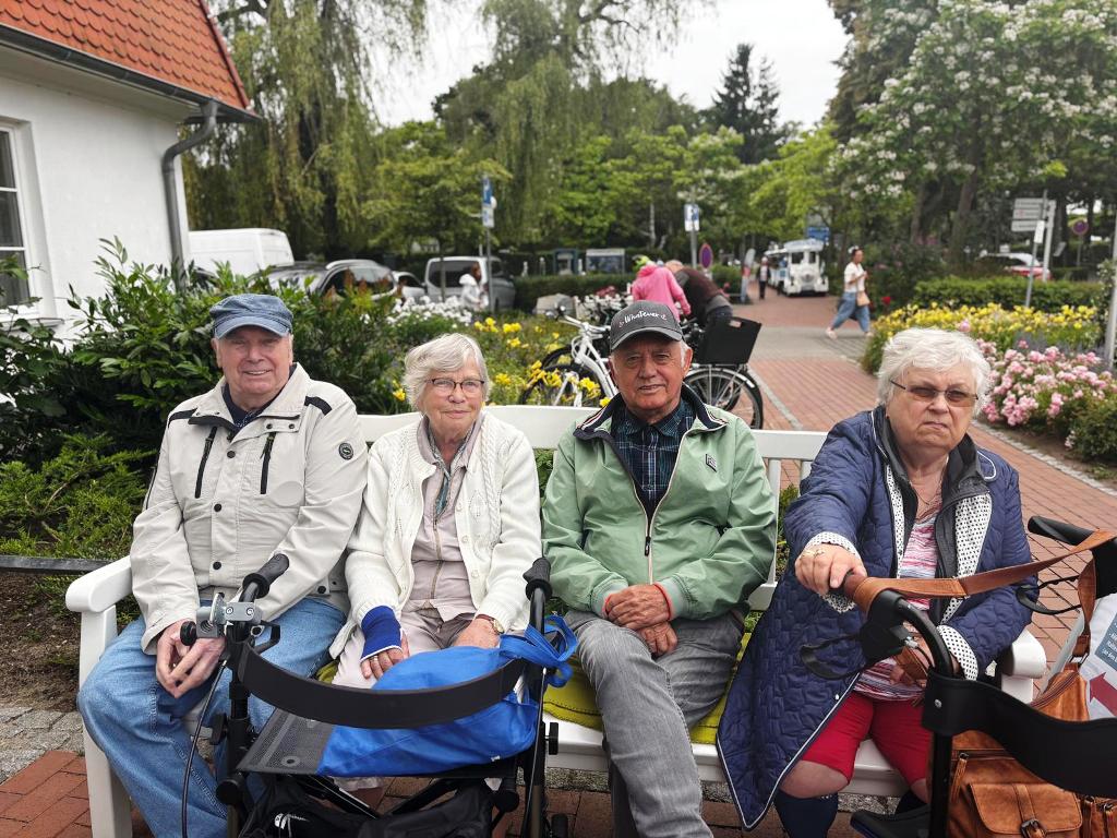 Vier ältere Personen sitzen auf einer Bank im Freien.