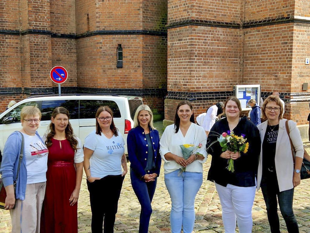 Gruppe von sieben Frauen vor einem Backsteingebäude