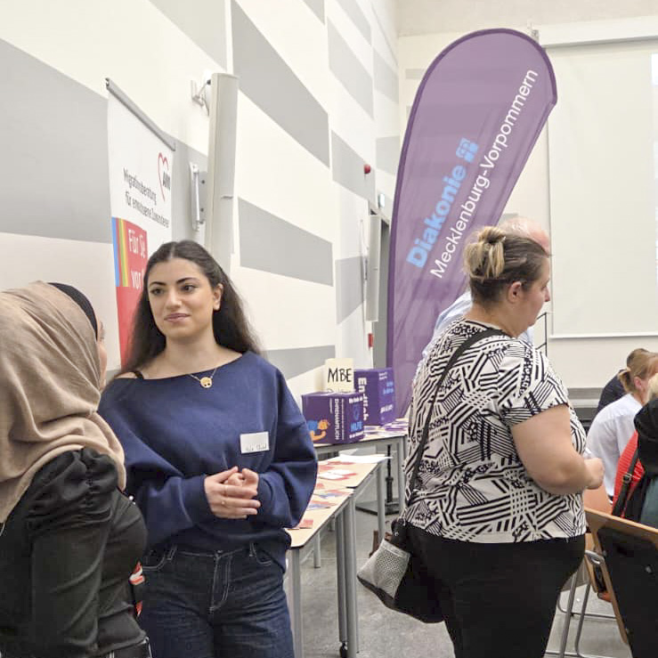 Menschen im Gespräch bei einer Veranstaltung mit Infoständen