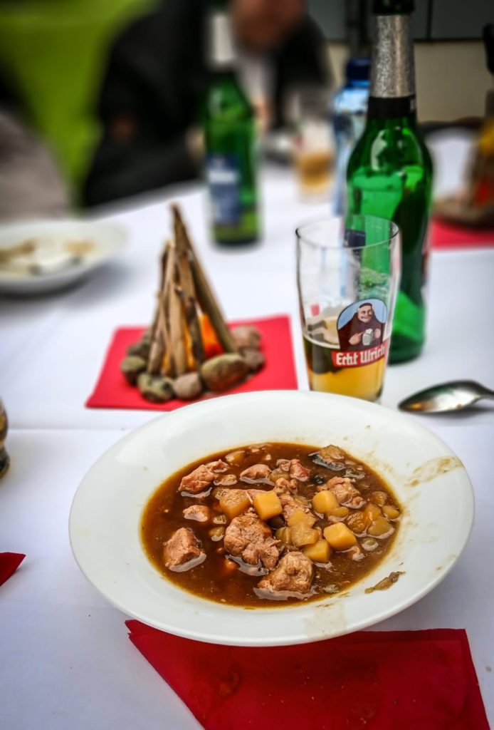 Ein Teller mit Gulasch und Gemüse auf einem Tisch.