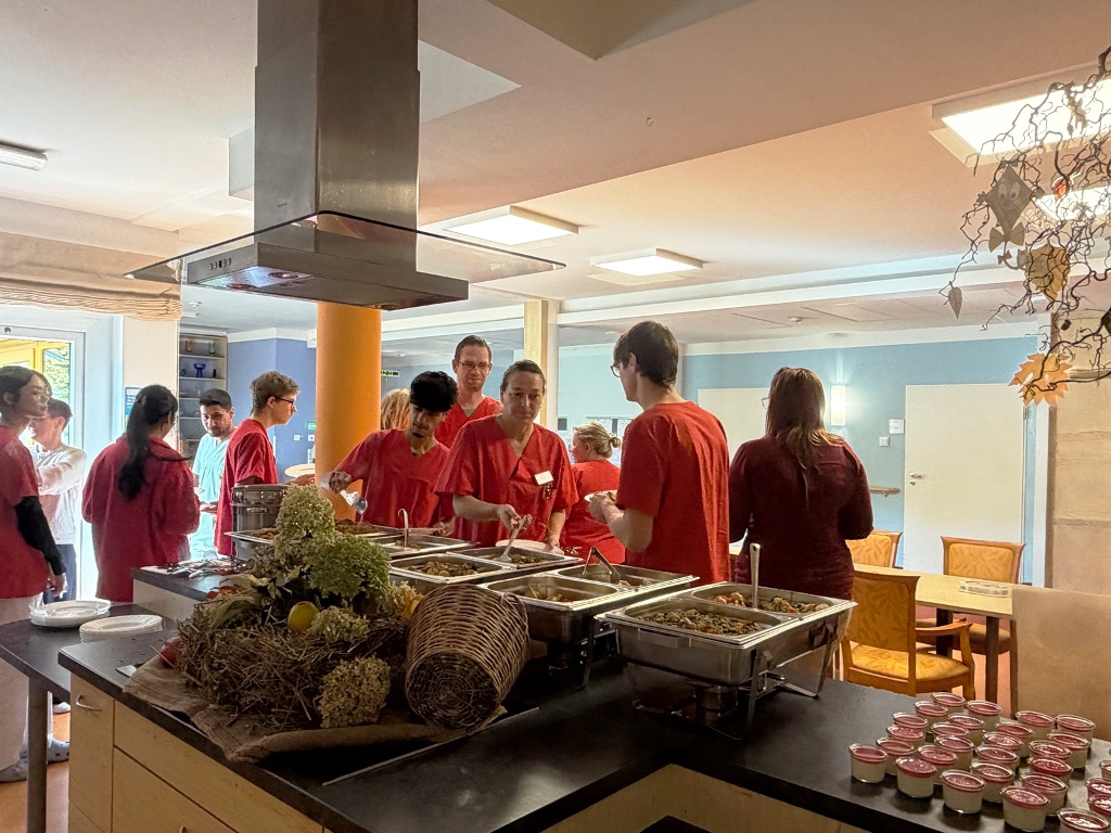 Personen in roter Kleidung in einer Kantine beim Essenfassen