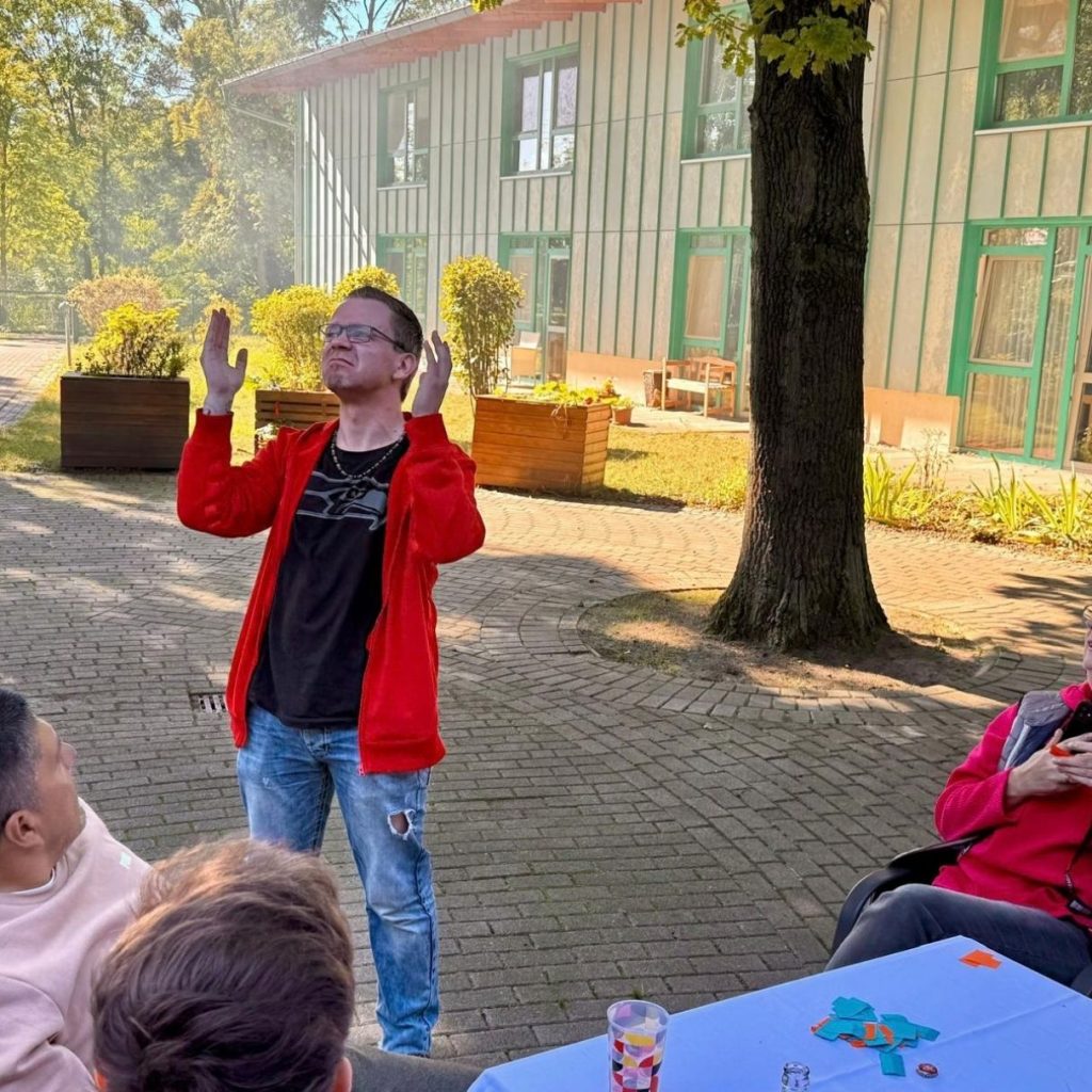 Ein Mann in roter Jacke erklärt etwas gestenreich im Freien.